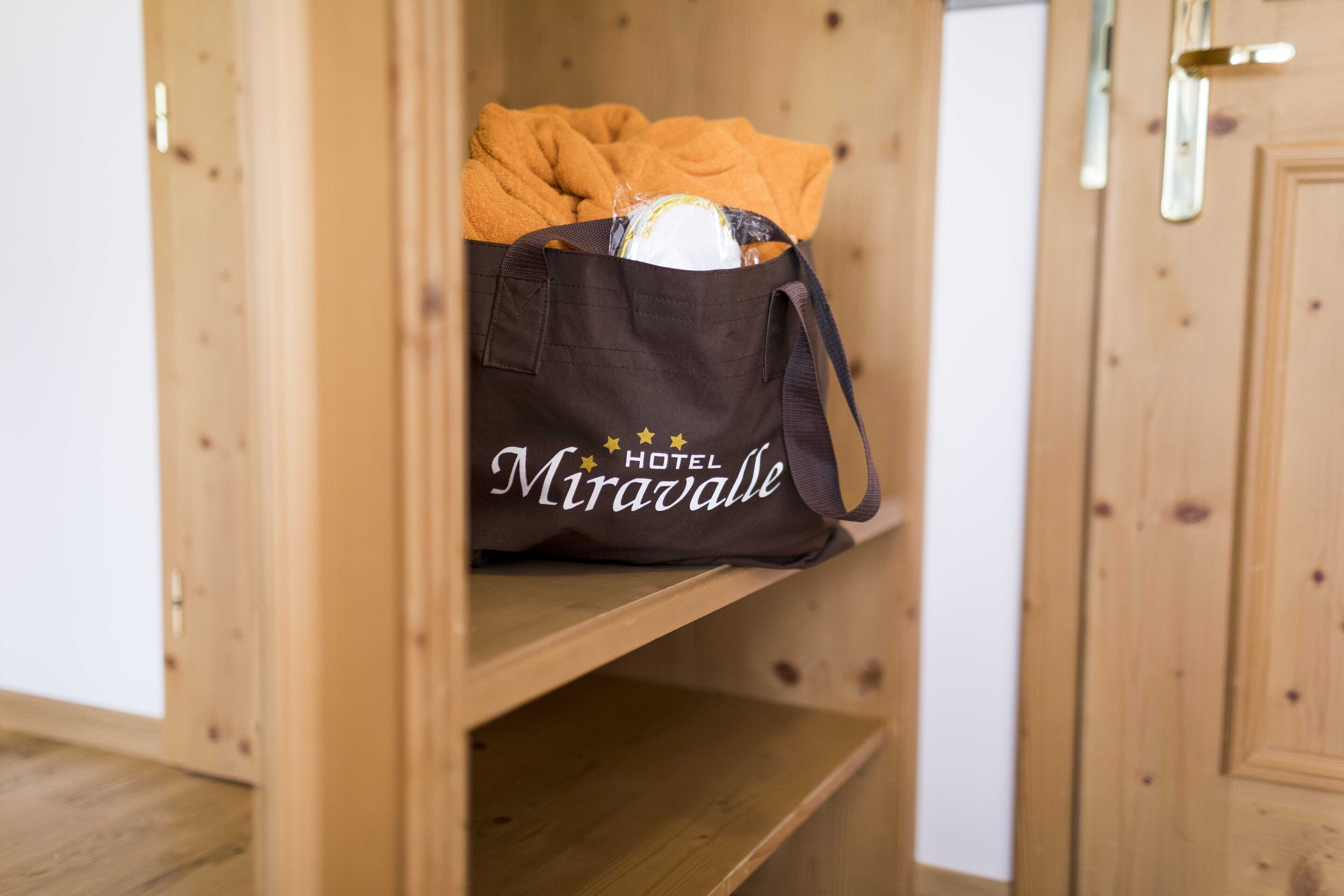 Una estantería de madera con una bolsa marrón que lleva la etiqueta "Miravalle Hotel" y contiene un objeto amarillo.