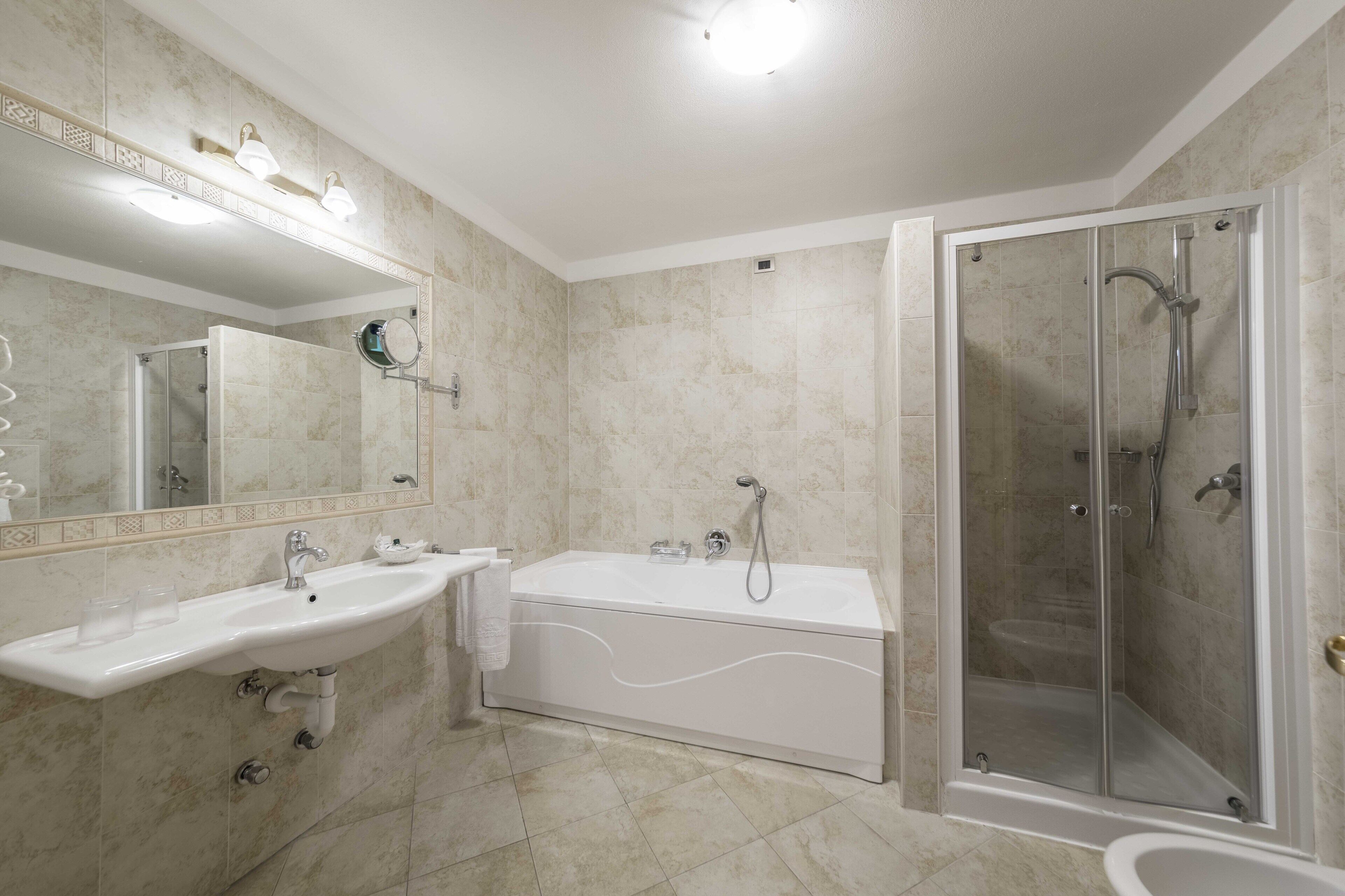 Une salle de bain avec deux lavabos, une baignoire et une douche à parois de verre.