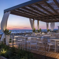 Enjoy ocean views from this rooftop terrace with a pergola, seating area, and potted plants.