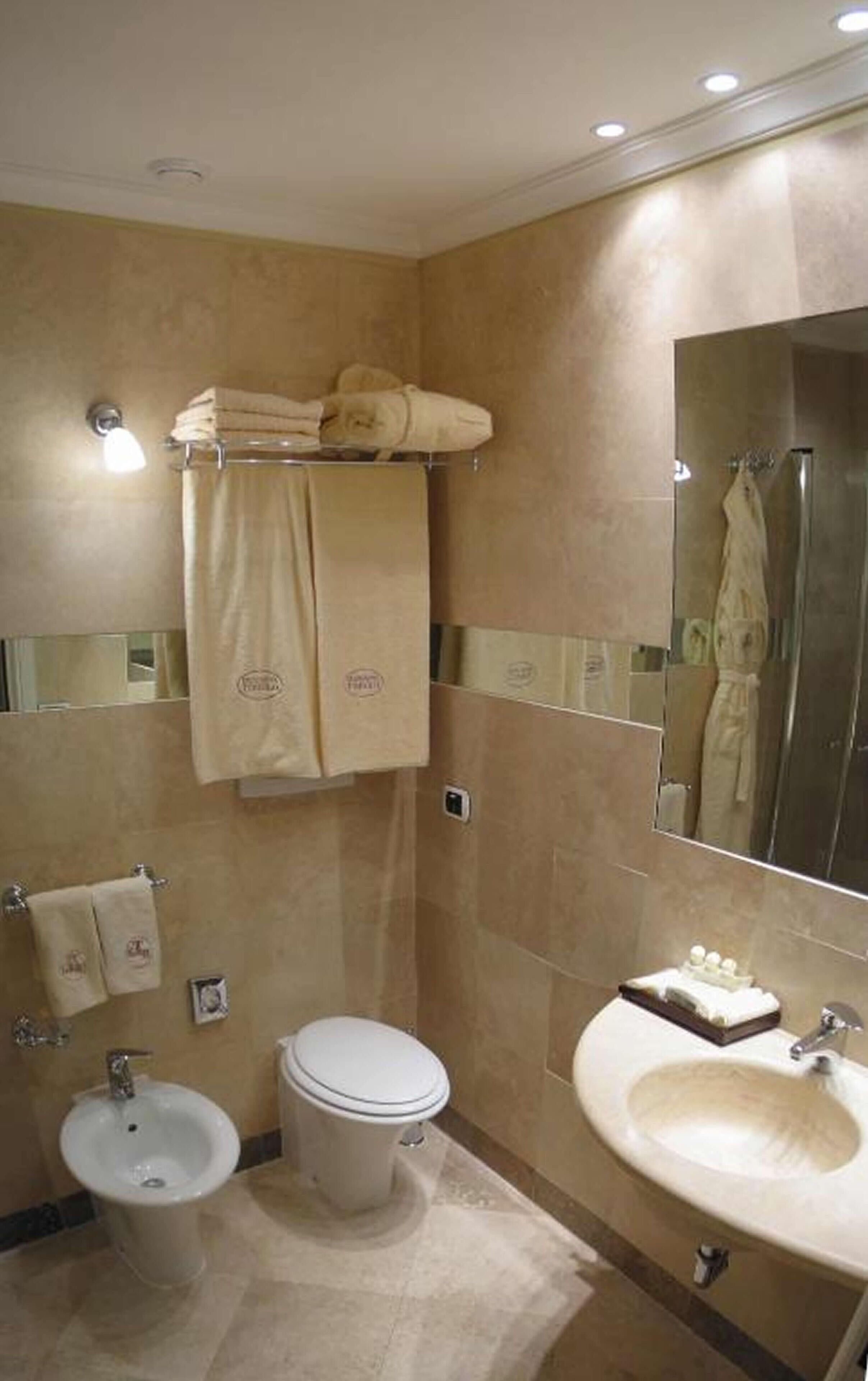 Une salle de bain comprenant des toilettes, un bidet, un lavabo et un porte-serviettes avec des serviettes.