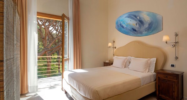 Un dormitorio con una cama grande, un cuadro en la pared y vistas a árboles desde la ventana.