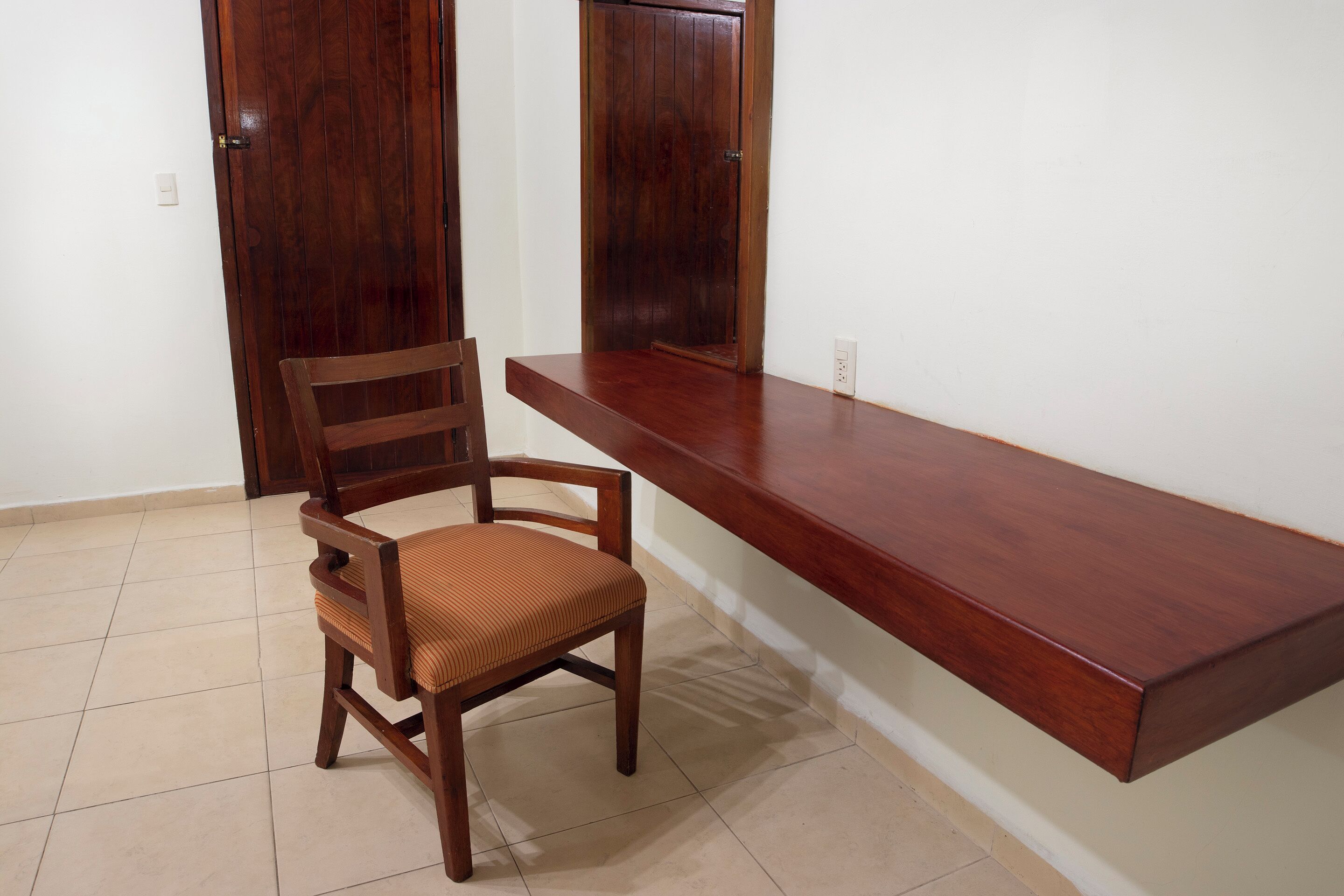 A wooden chair with a cushioned seat and backrest, positioned in front of a wooden counter.
