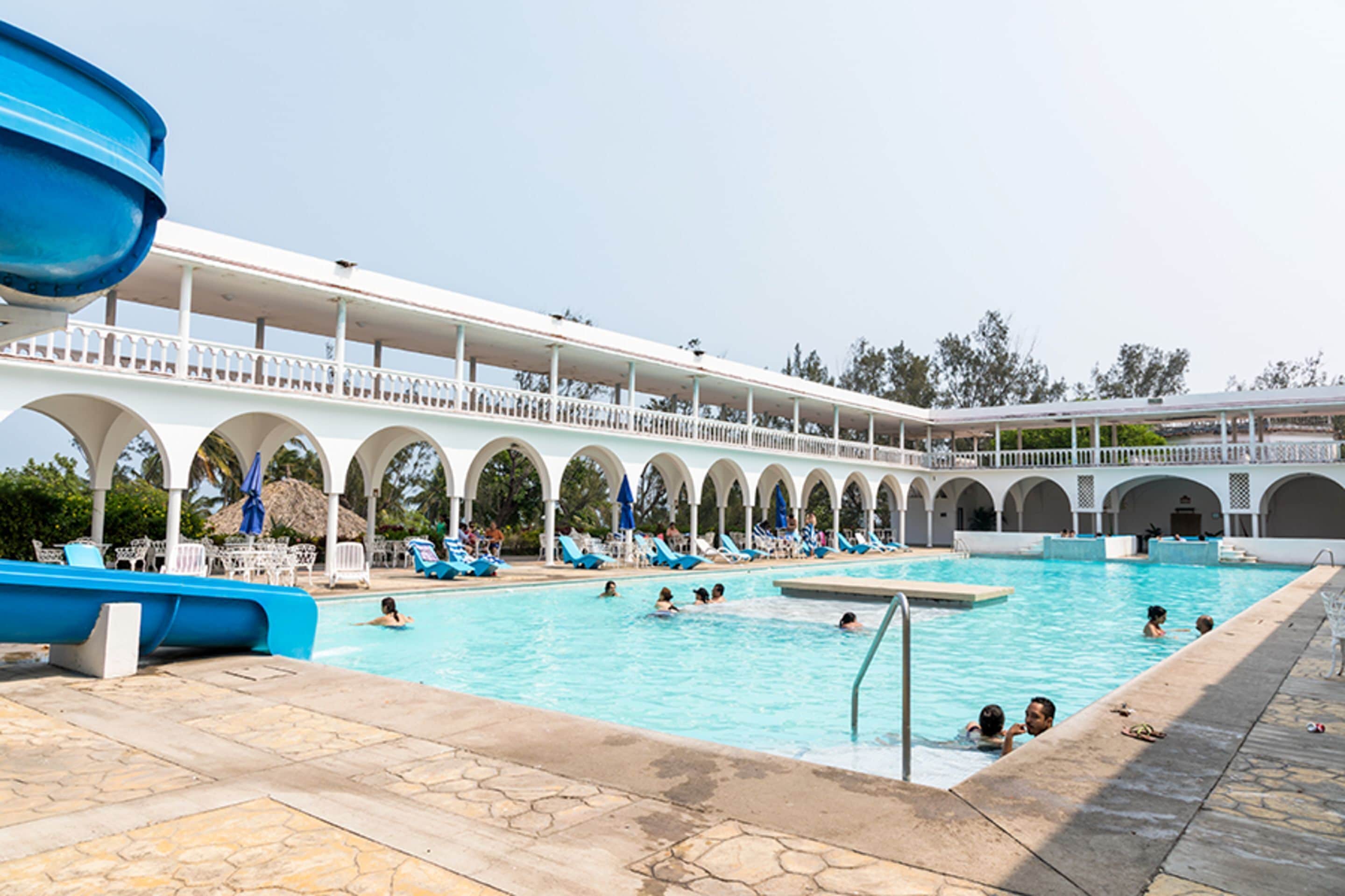 A swimming pool with a covered deck, multiple arches, and lounge chairs.