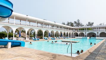 A swimming pool with a covered deck, multiple arches, and lounge chairs.