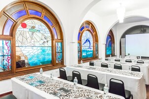 Un salón de conferencias con mesas, sillas y vidrieras de colores.