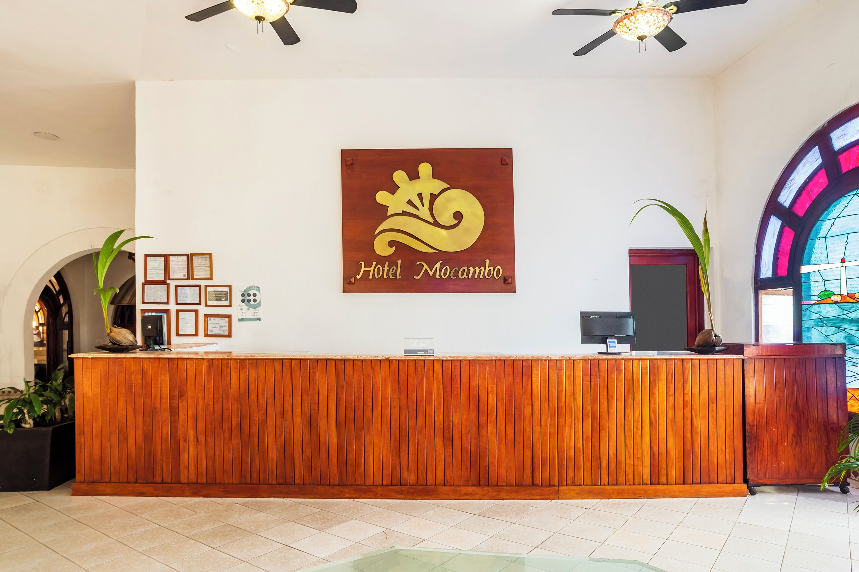 A reception desk with a wooden finish, a logo above it, and a stained glass window to the right.
