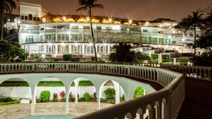 Un hotel de varios pisos con zona de piscina, que presenta fachada blanca y varios balcones.
