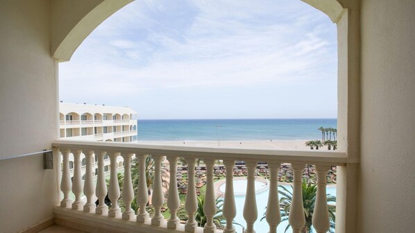 Un balcón con vista a la playa y una piscina.
