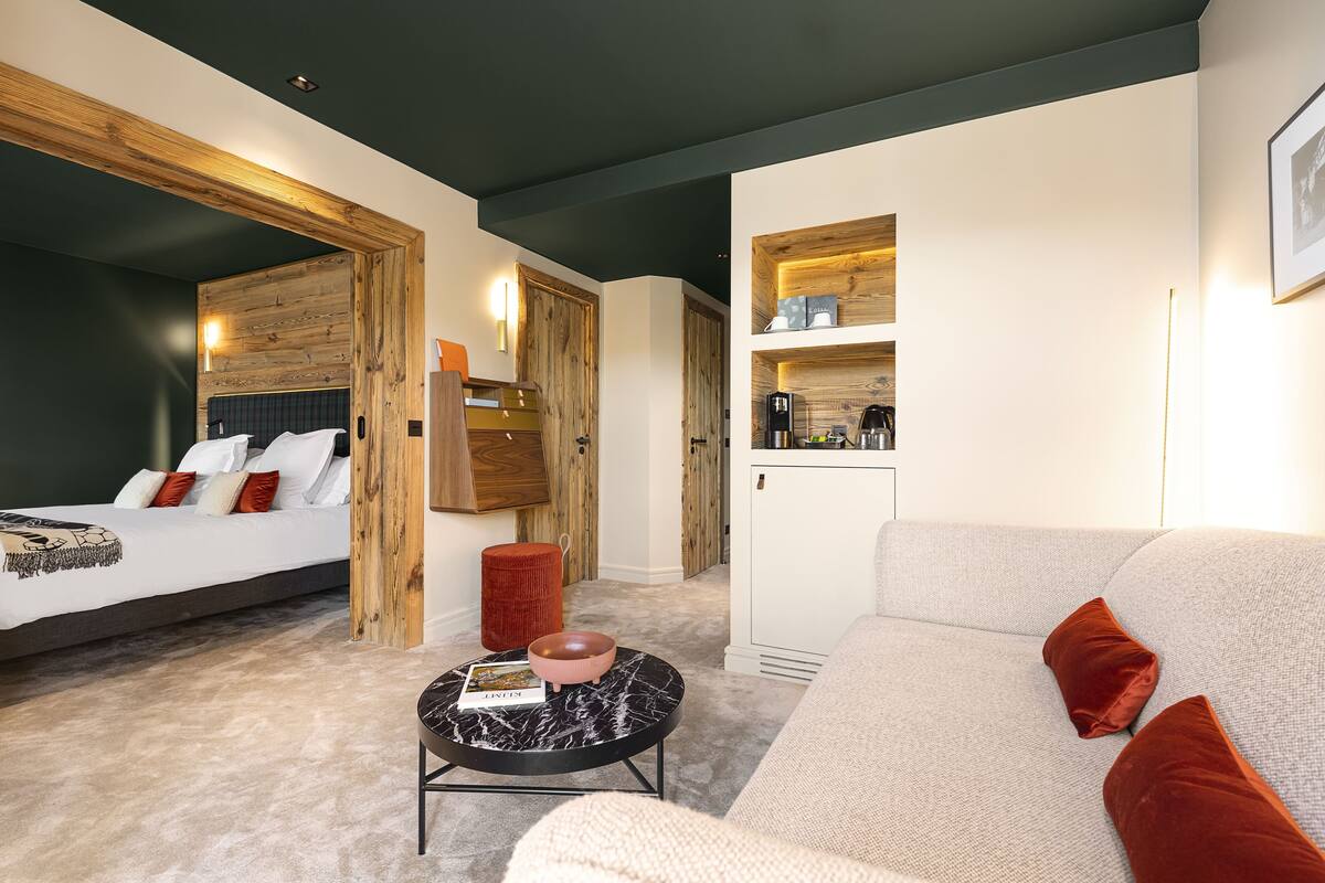 Quarto moderno com cama, mesa de centro redonda e sofá.