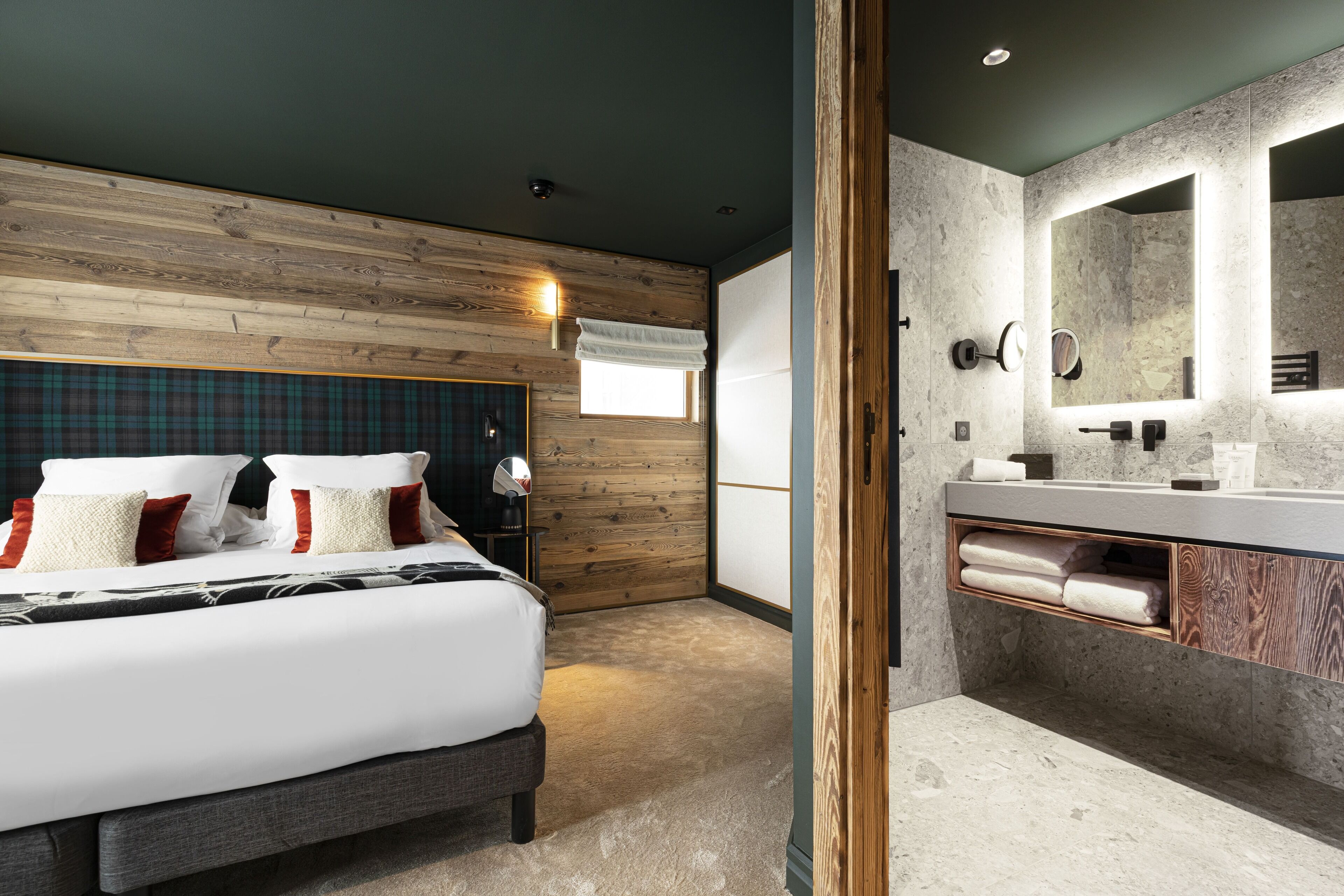 Un dormitorio moderno con cabecera de madera, cama grande, mesita de noche y tocador.