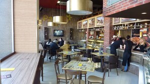 A restaurant interior with wooden tables and chairs, a bar area, and a counter with staff.