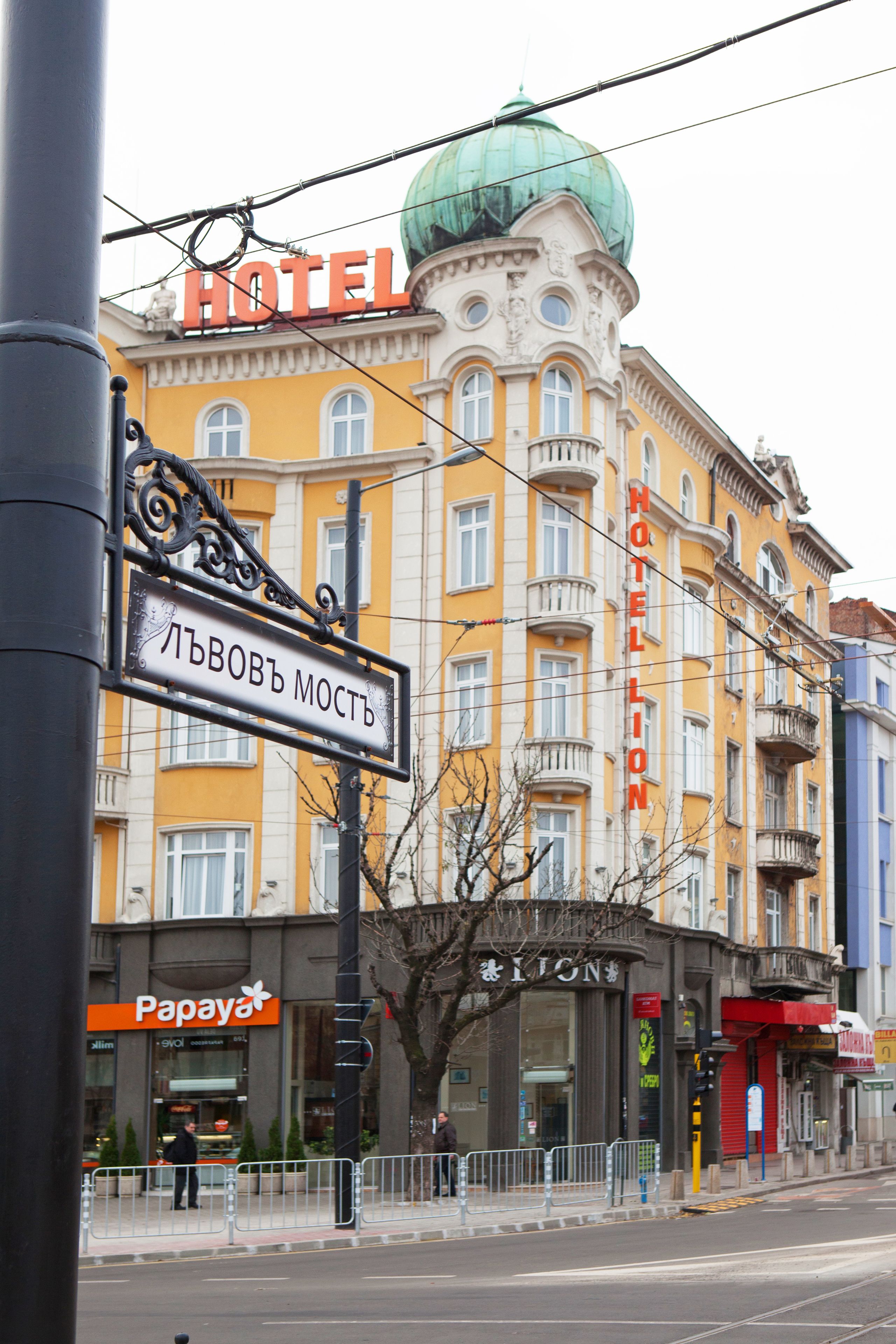 Ein Hotel mit gelber Fassade, einer grünen Kuppel und einem Schild, das angibt, dass es sich in der Nähe von Левовъ Мост befindet.