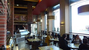Um café moderno com paredes de tijolo, balcão de café e grandes janelas.