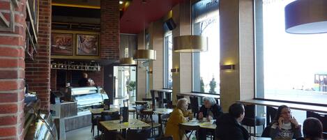 Un café moderne avec des murs en briques, un comptoir et de grandes fenêtres.