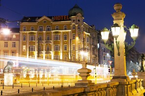 A hotel with a prominent 'HOTEL' sign, a statue, and ornate street lamps.