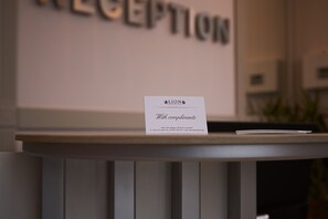 A reception desk with a sign that reads "LION With compliments" and a business card with contact information.