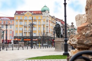 A hotel with multiple floors, a prominent lion statue, and a green dome on the roof.