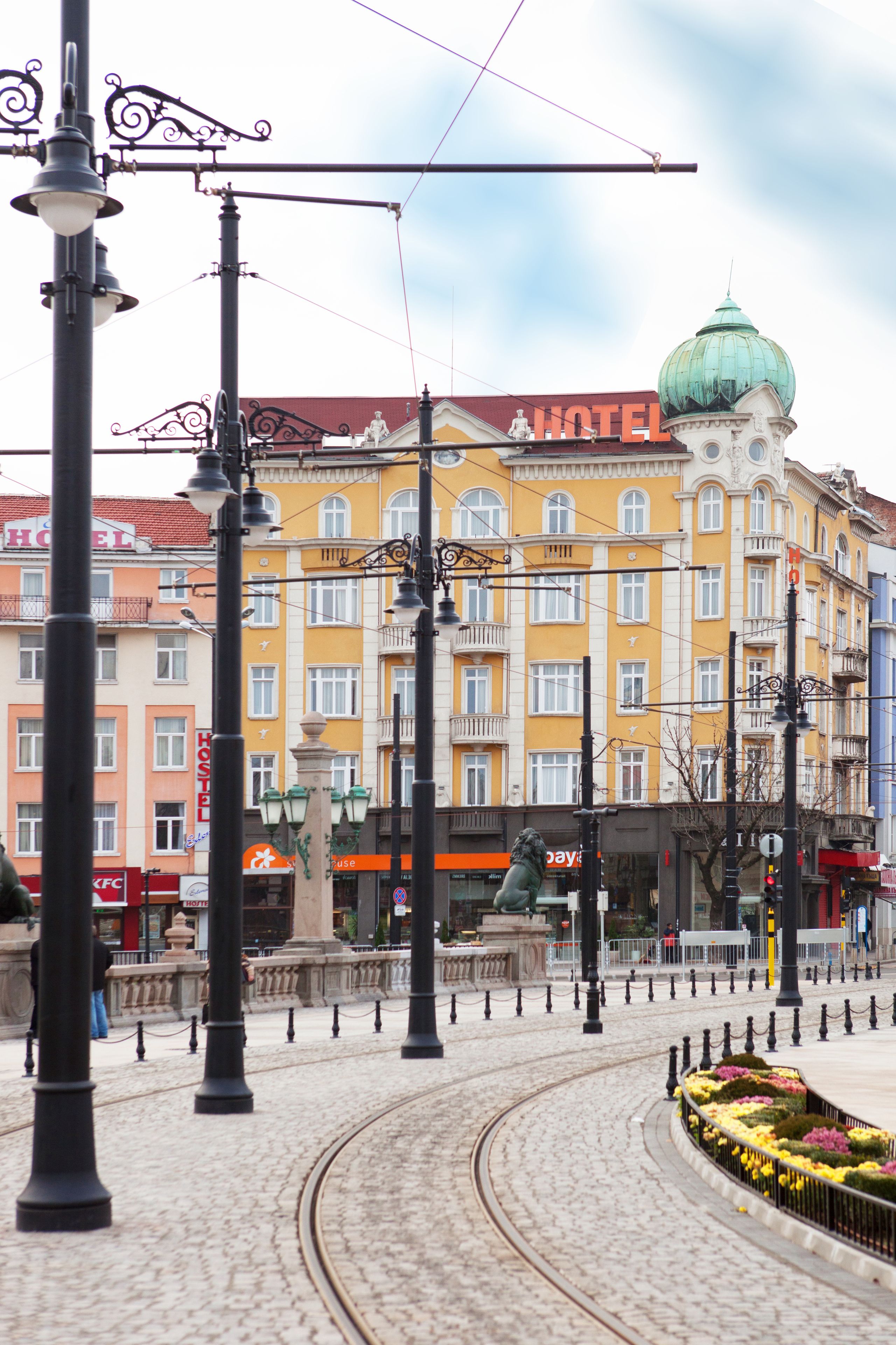 A historic building with a green dome, yellow and orange facades, and a sign reading "HOTEL".