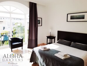 Een hotelkamer met een bed, een stoel, een klein tafeltje en uitzicht.