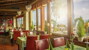A restaurant with wooden beams, green tablecloths, and red chairs.