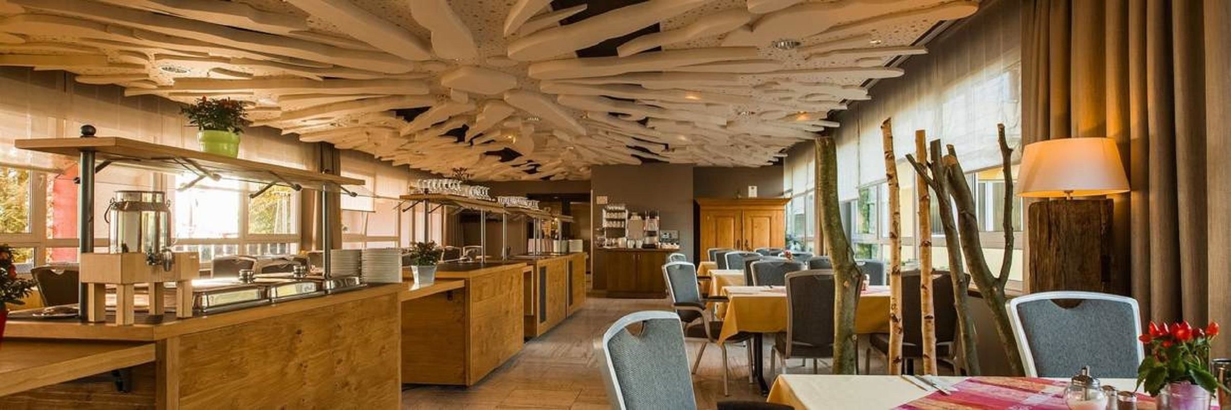Un restaurant amb un disseny de sostre singular, mobles de fusta i una zona de bar.