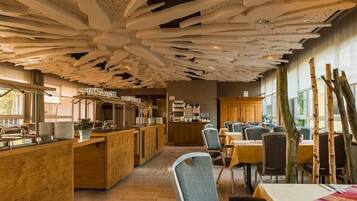 Un restaurante con un diseño de techo único, mobiliario de madera y una zona de bar.