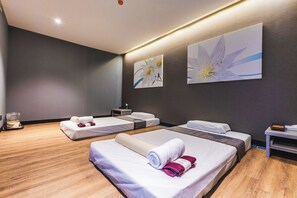 Een hotelkamer met drie bedden, houten vloeren en kunstwerken aan de muren.