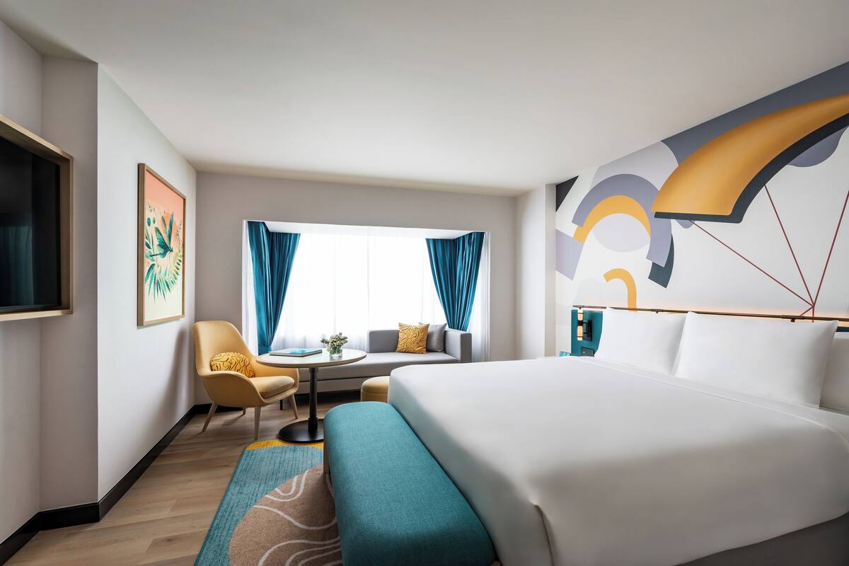 Een hotelkamer met een bed, een bank, een stoel, een tafeltje en een televisie.