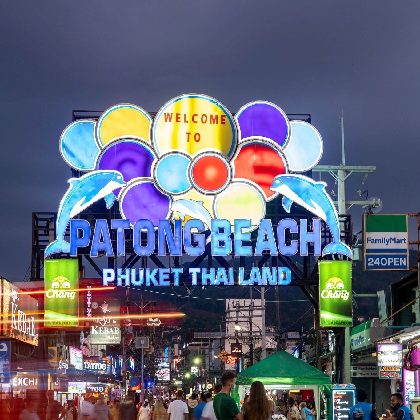 Un letrero de bienvenida llamativo en la playa de Patong, Phuket, Tailandia, con luces circulares de colores y un gráfico de delfín.