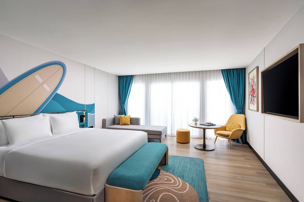 Een moderne hotelkamer met een groot bed, een bank, een tafeltje en een televisie.