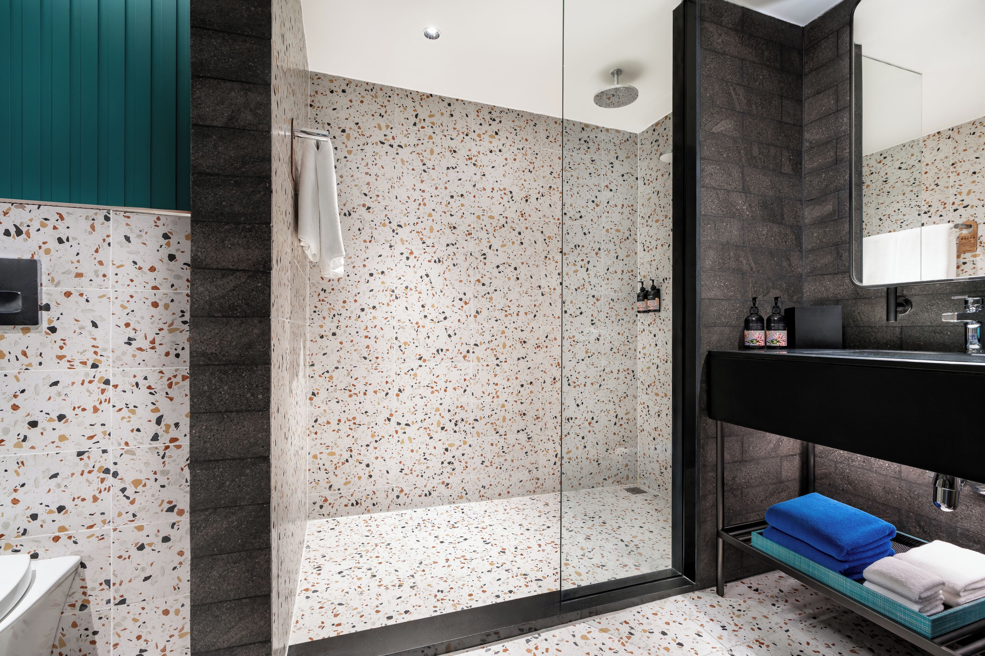 Ein modernes Badezimmer mit Dusche, Waschbecken mit schwarzer Arbeitsplatte und Spiegel über dem Waschbecken.