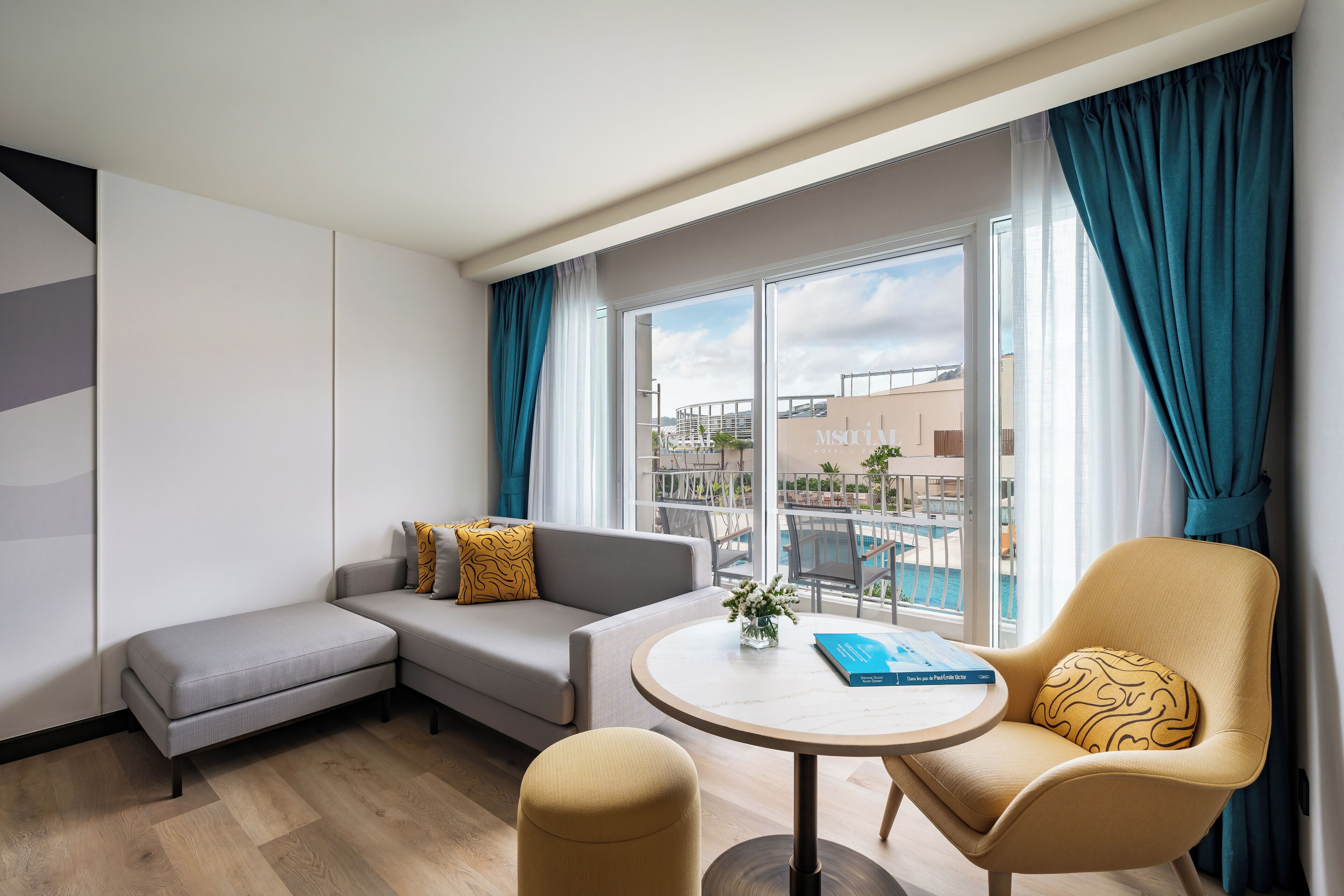 Ein modernes Hotelzimmer mit Sofa, Sesseln und rundem Tisch.