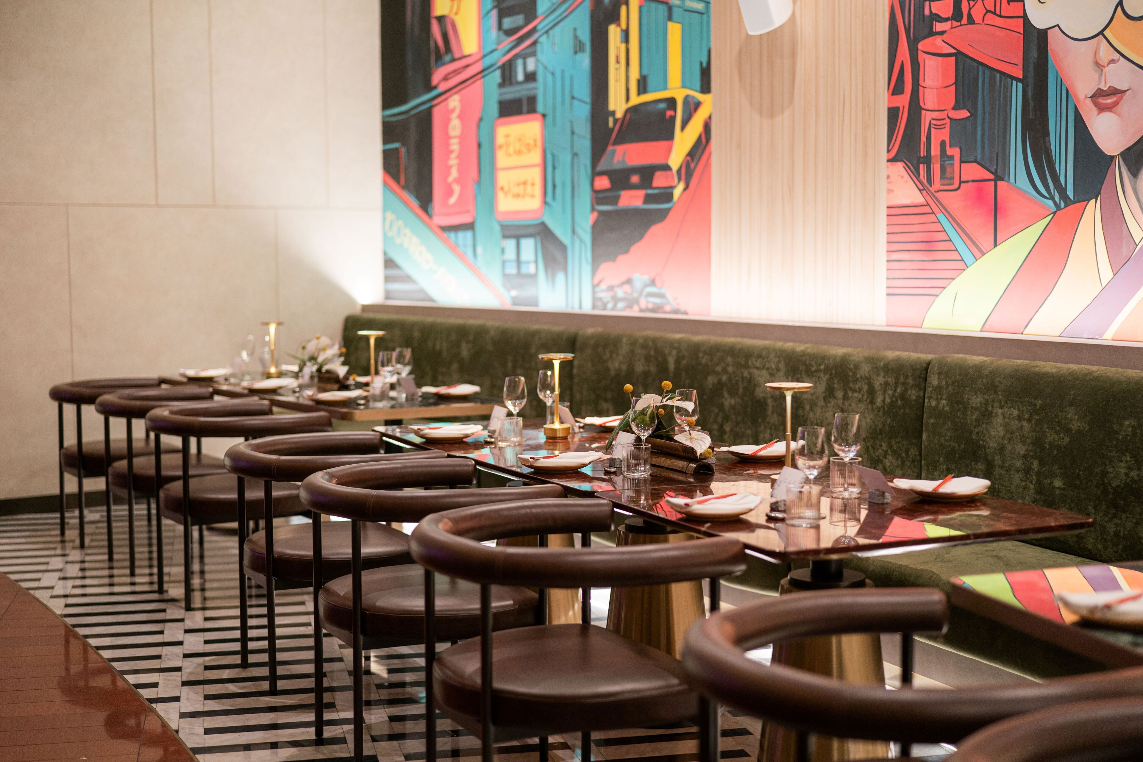 Un restaurante con varias mesas y sillas, un suelo estampado y un mural colorido en la pared.