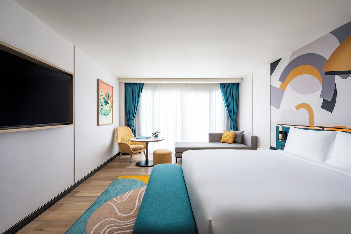 A hotel room with a bed, a sofa, a desk, and a TV.