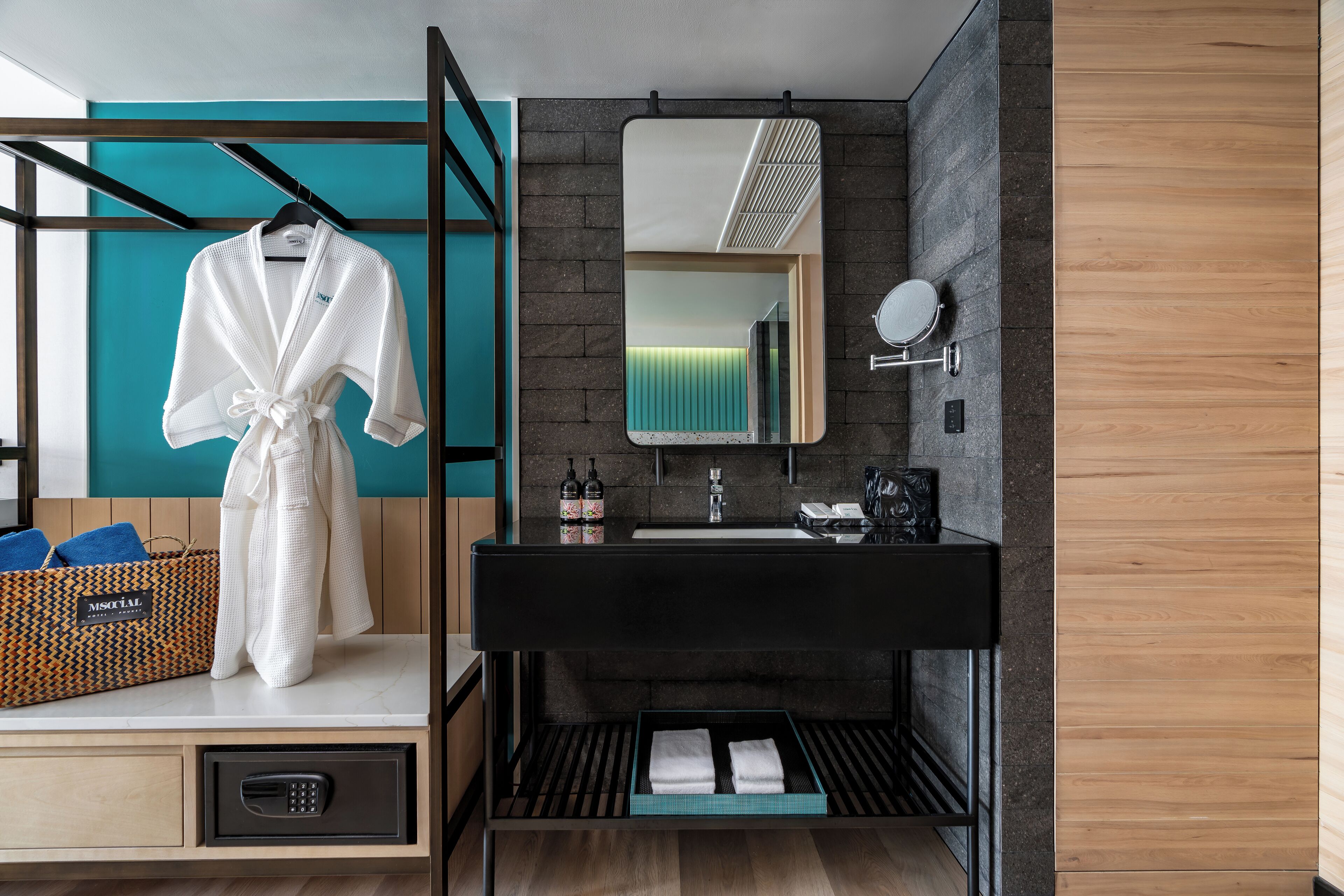 A modern bathroom with a black vanity, a mirror, a towel rack, and a storage basket.