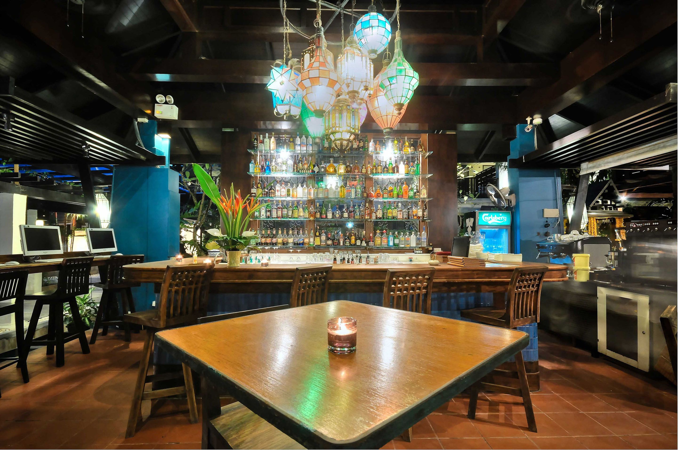 Un área de bar con una mesa de madera, sillas y una variedad de botellas en estanterías.
