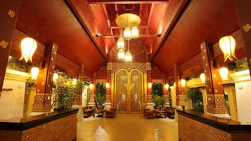 A reception area with a wooden reception desk, multiple seating arrangements, and a decorative entrance with a patterned door.