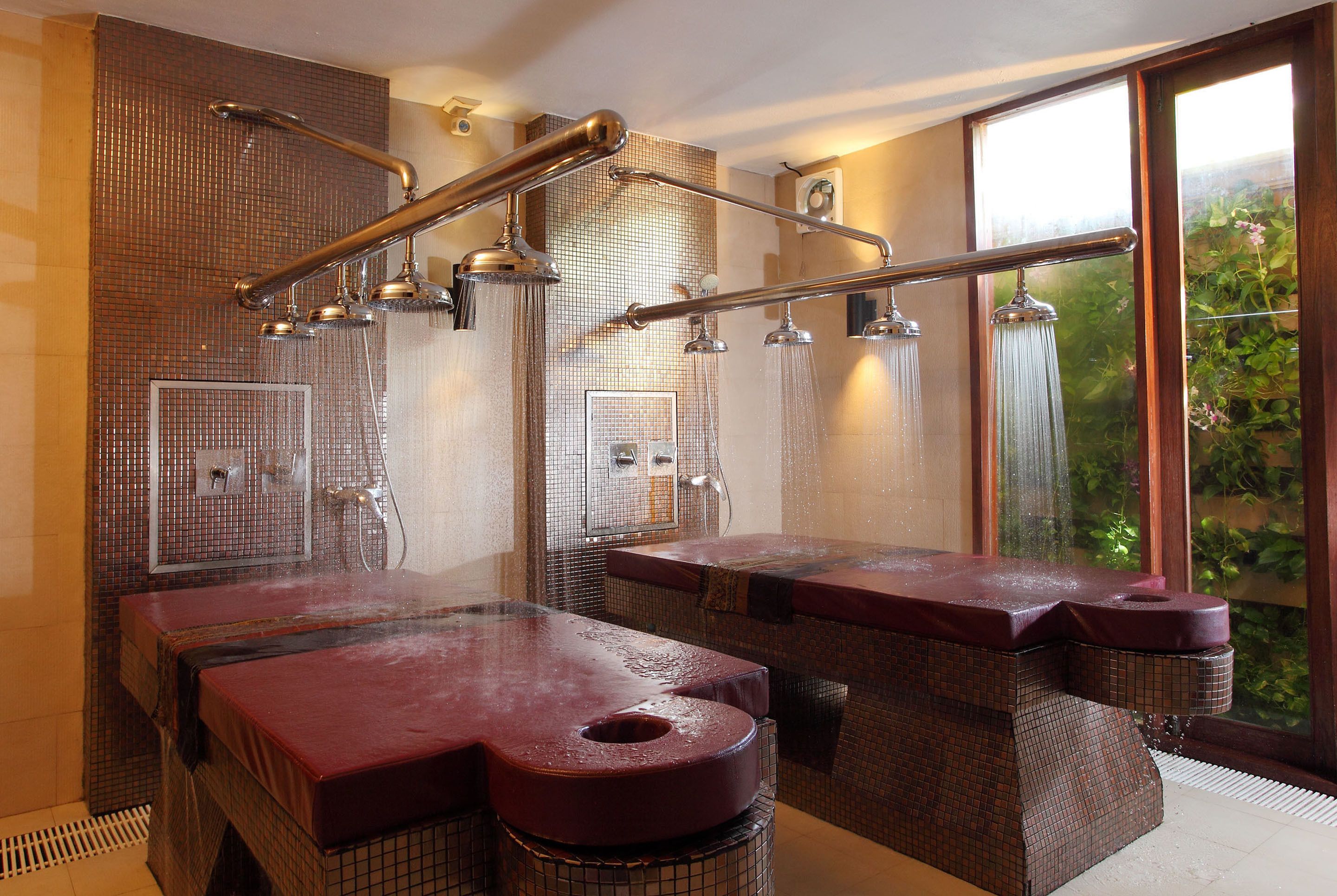Ein Wellnessbereich mit mehreren Whirlpools und einem großen Fenster mit Blick auf Grünflächen.