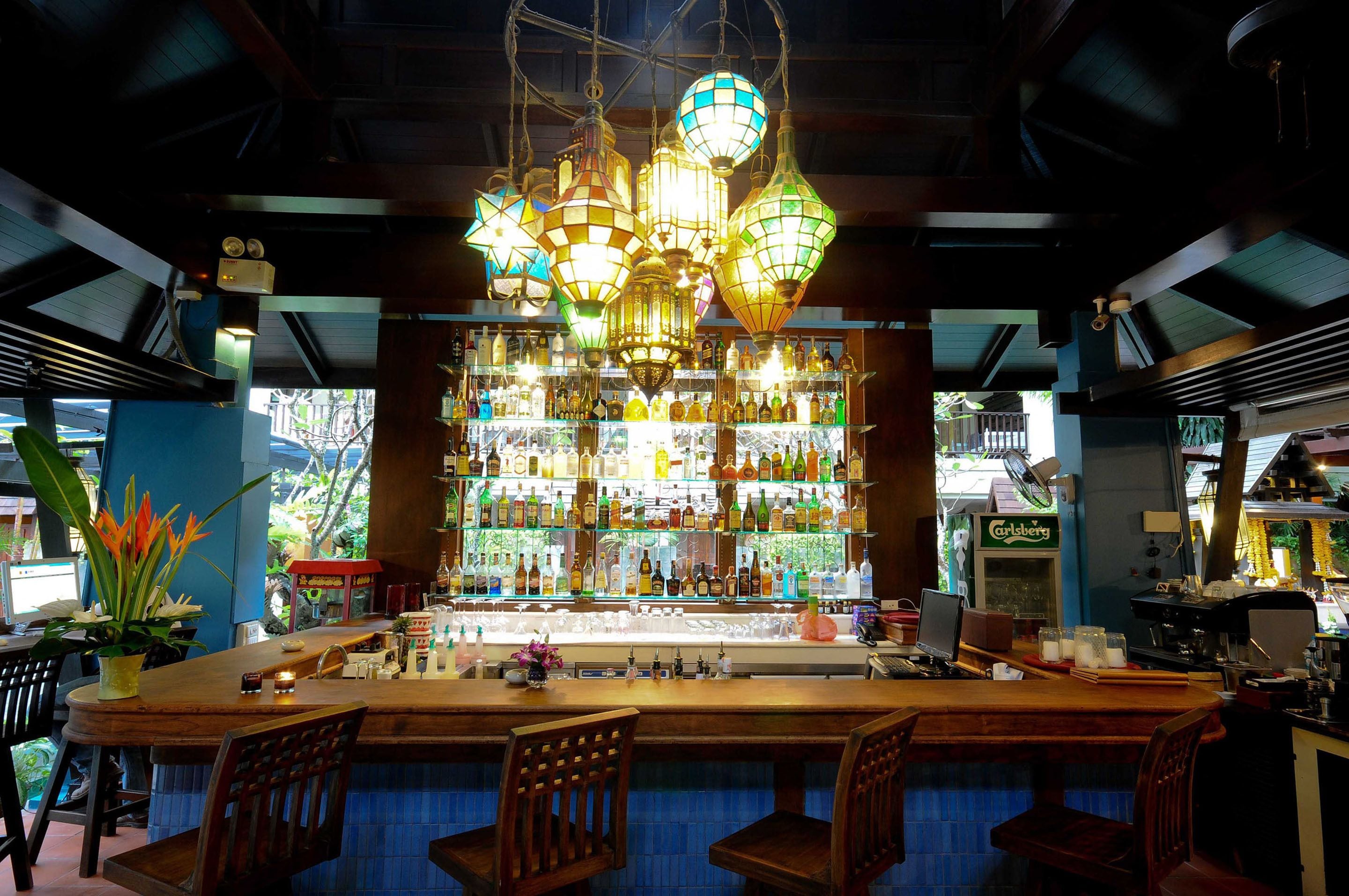 Un bar amb una barra de fusta, diverses lluminàries penjants i una varietat de garrafes a les estanteries.