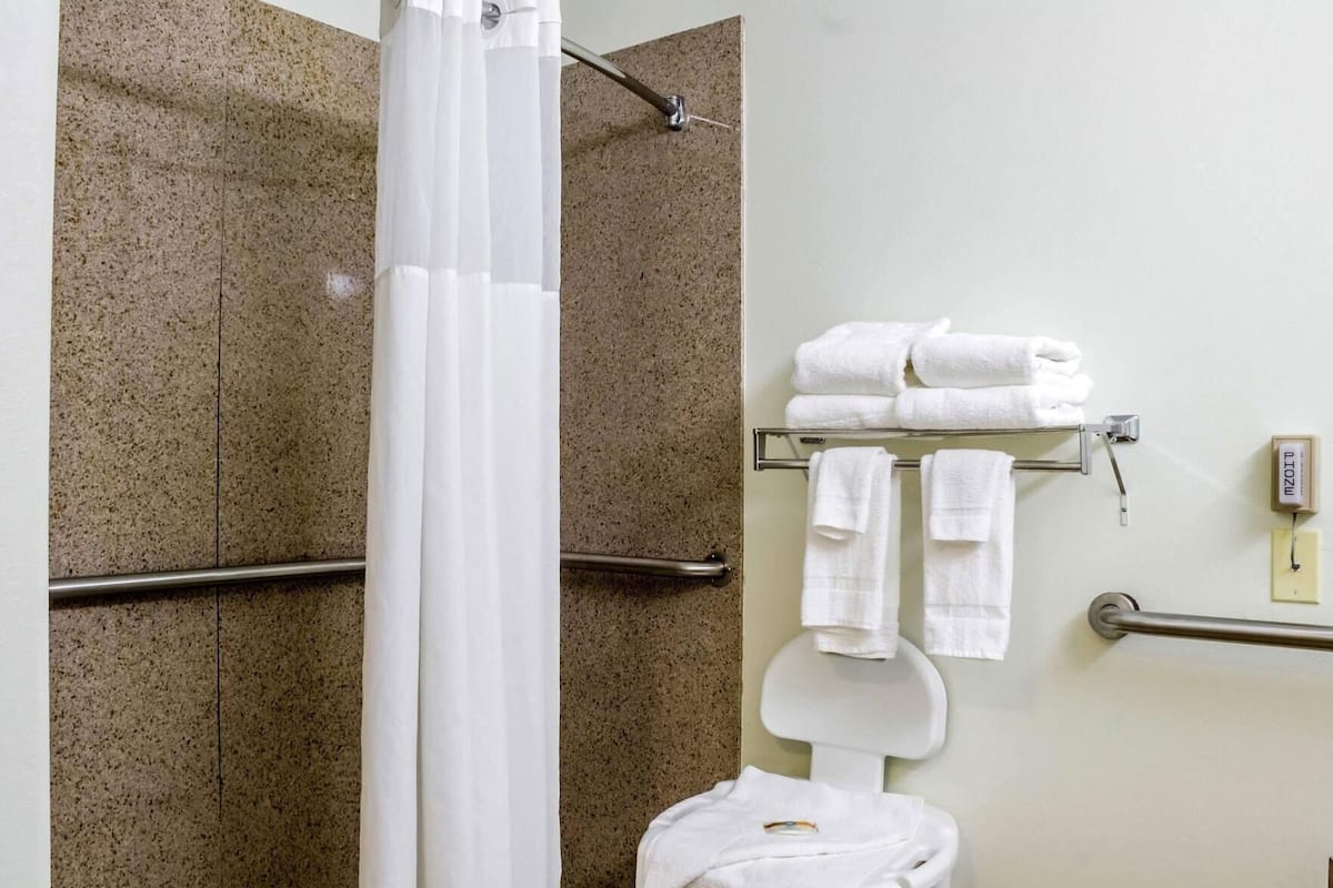 Ein Badezimmer mit Dusche, Toilette und Handtuchhalter mit Handtüchern.