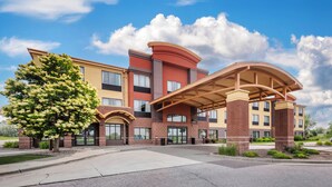 A multi-story hotel with a covered entrance, brick facade, and a large tree in front. - Clarion Pointe Sioux Falls Airport (Sioux Falls)