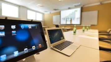 A conference room with a laptop, a tablet, and a projector screen displaying a presentation.