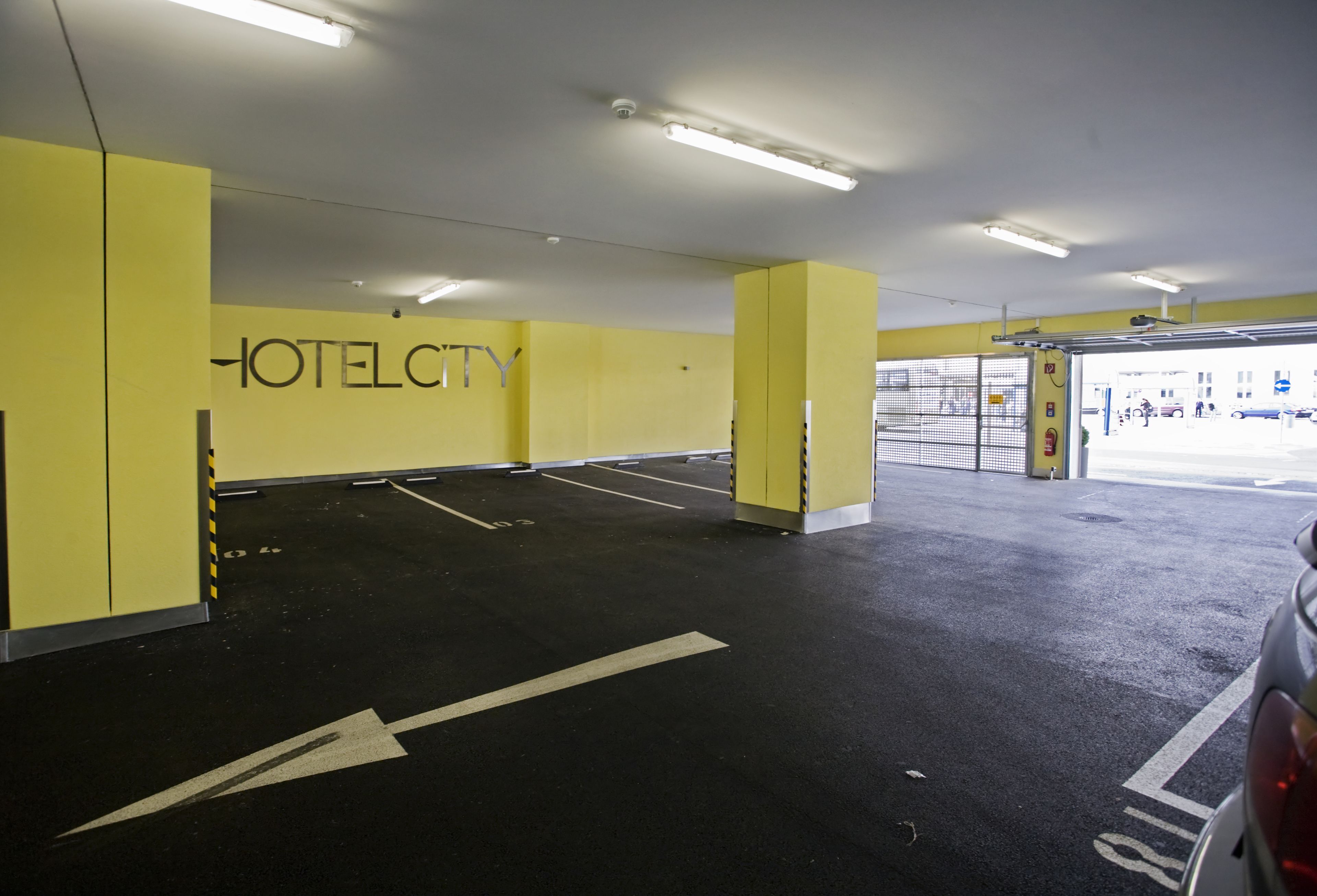 Een parkeergarage van een hotel met gele muren en een bord waarop 'HOTEL CITY' staat.