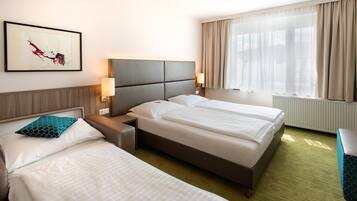 A hotel room with two beds, a headboard, bedside lamps, a framed artwork, and a window with curtains.
