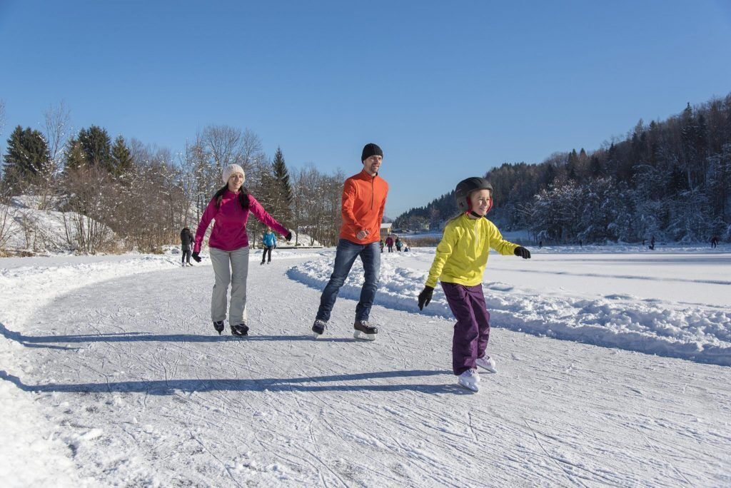 A snowy outdoor area with people walking and one person on skis.