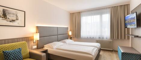 Una habitación de hotel con cama, sofá, televisor y un cuadro en la pared.