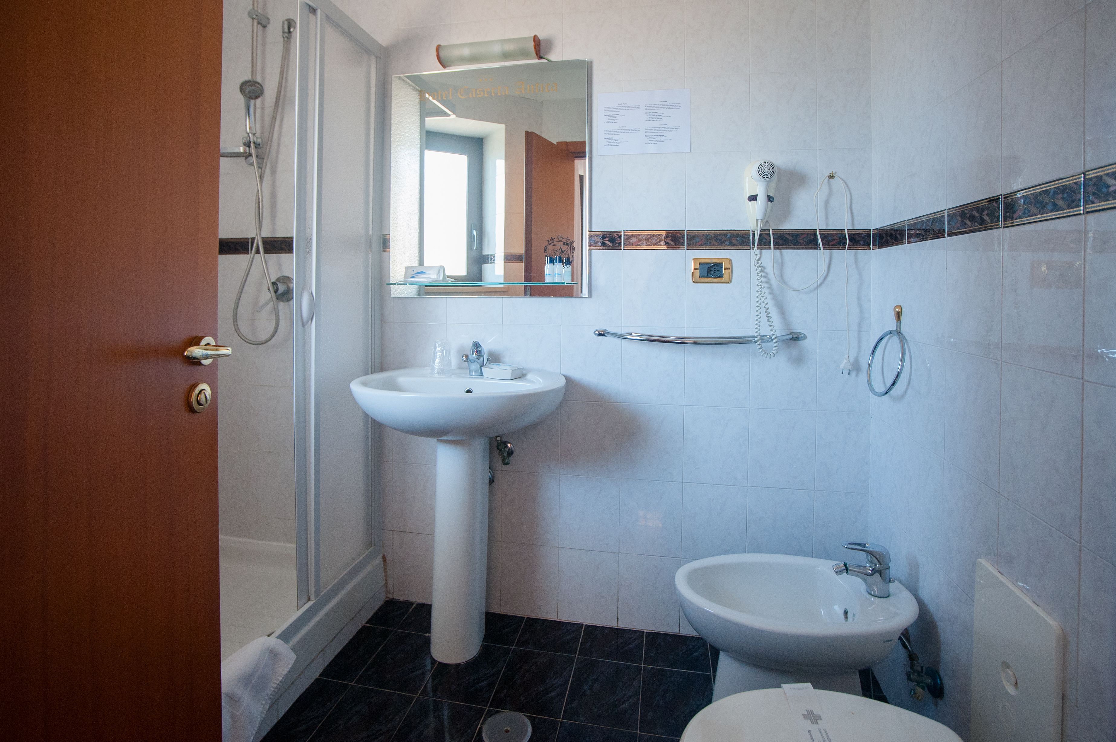 Une salle de bain avec une douche, deux lavabos, un miroir et un porte-serviettes.
