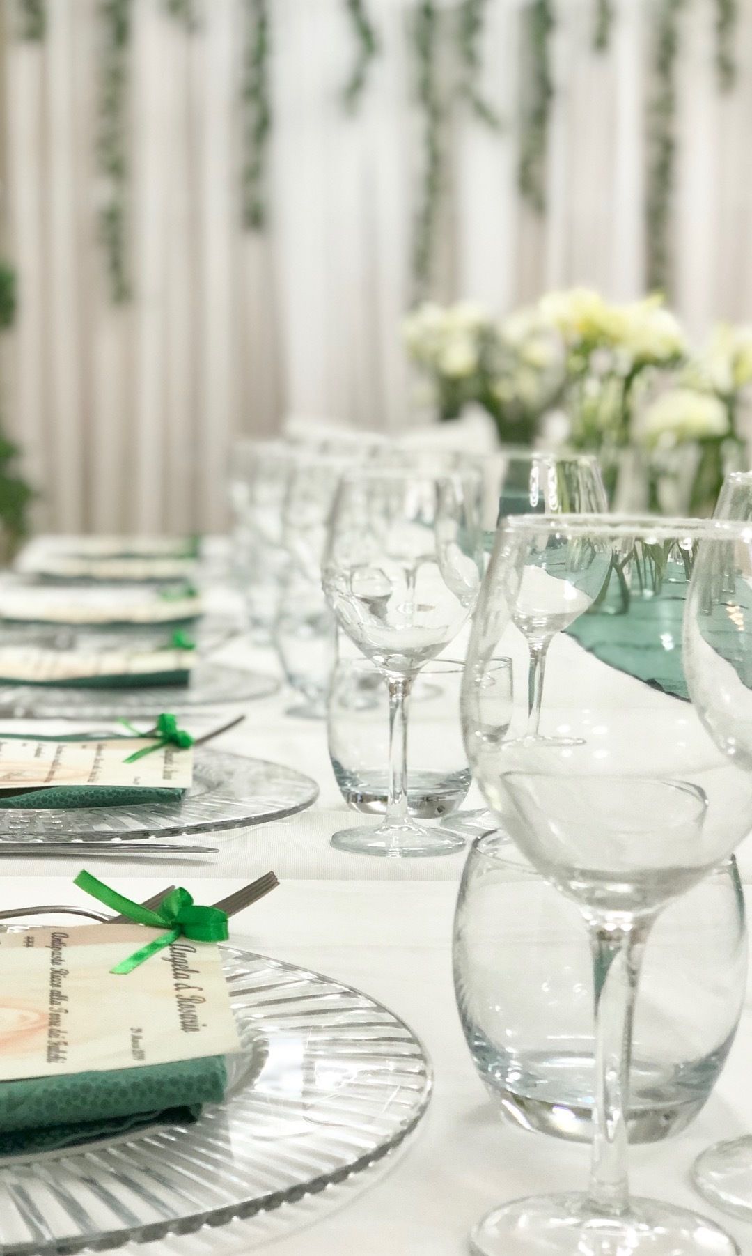 A table set with clear glassware and plates, with a green ribbon on one plate.