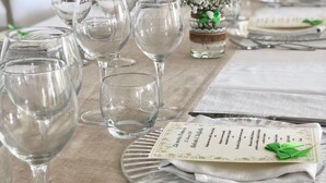 Una mesa dispuesta para un evento formal, con copas de vino, cubiertos y una carta.