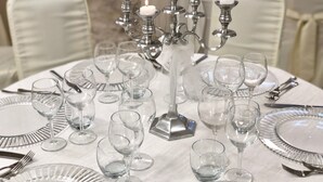 Mesa dispuesta para una cena formal, con copas de cristal, cubiertos y un candelabro con velas encendidas.